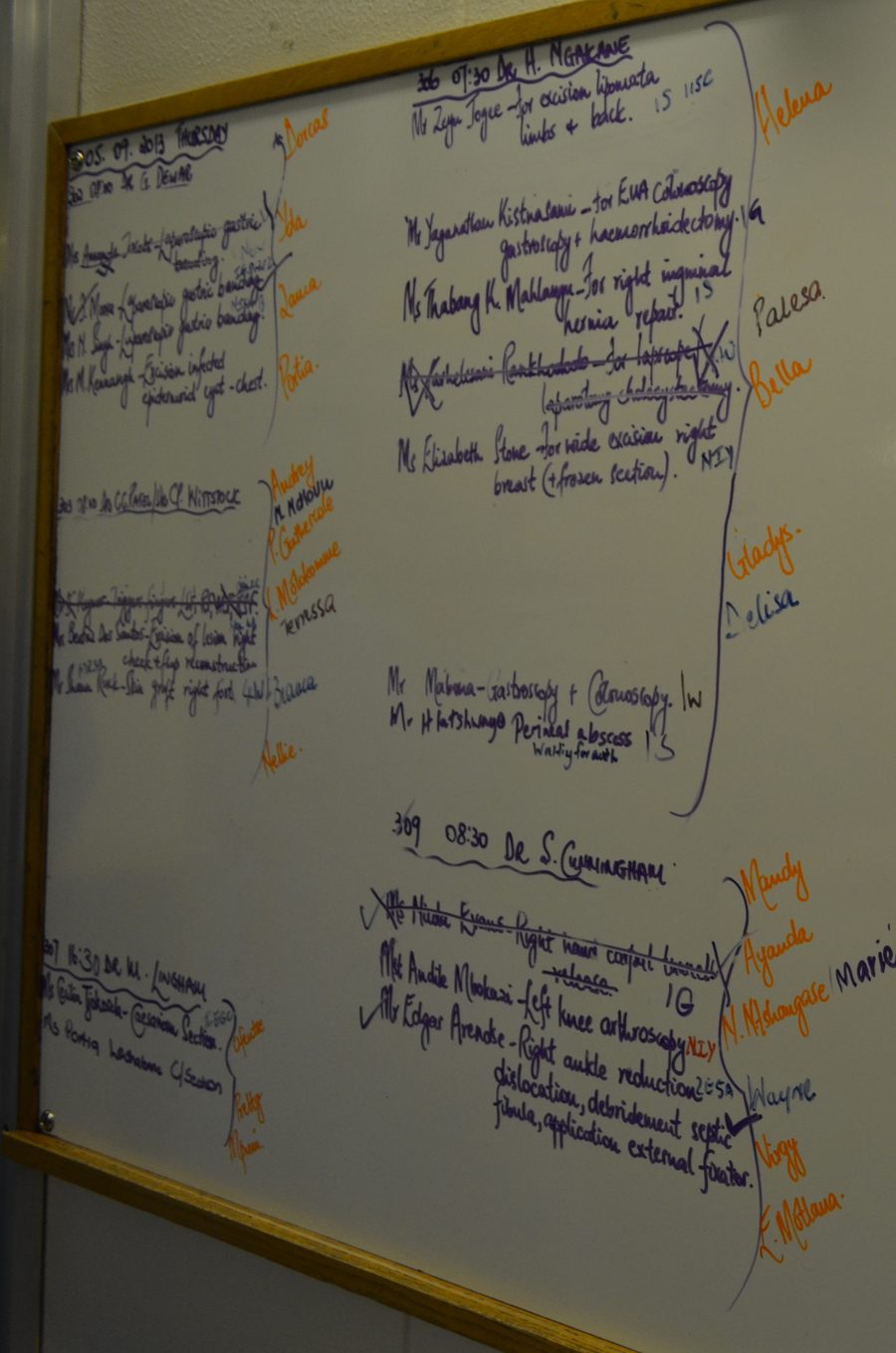 A whiteboard filled with handwritten patient and handover notes across several columns.