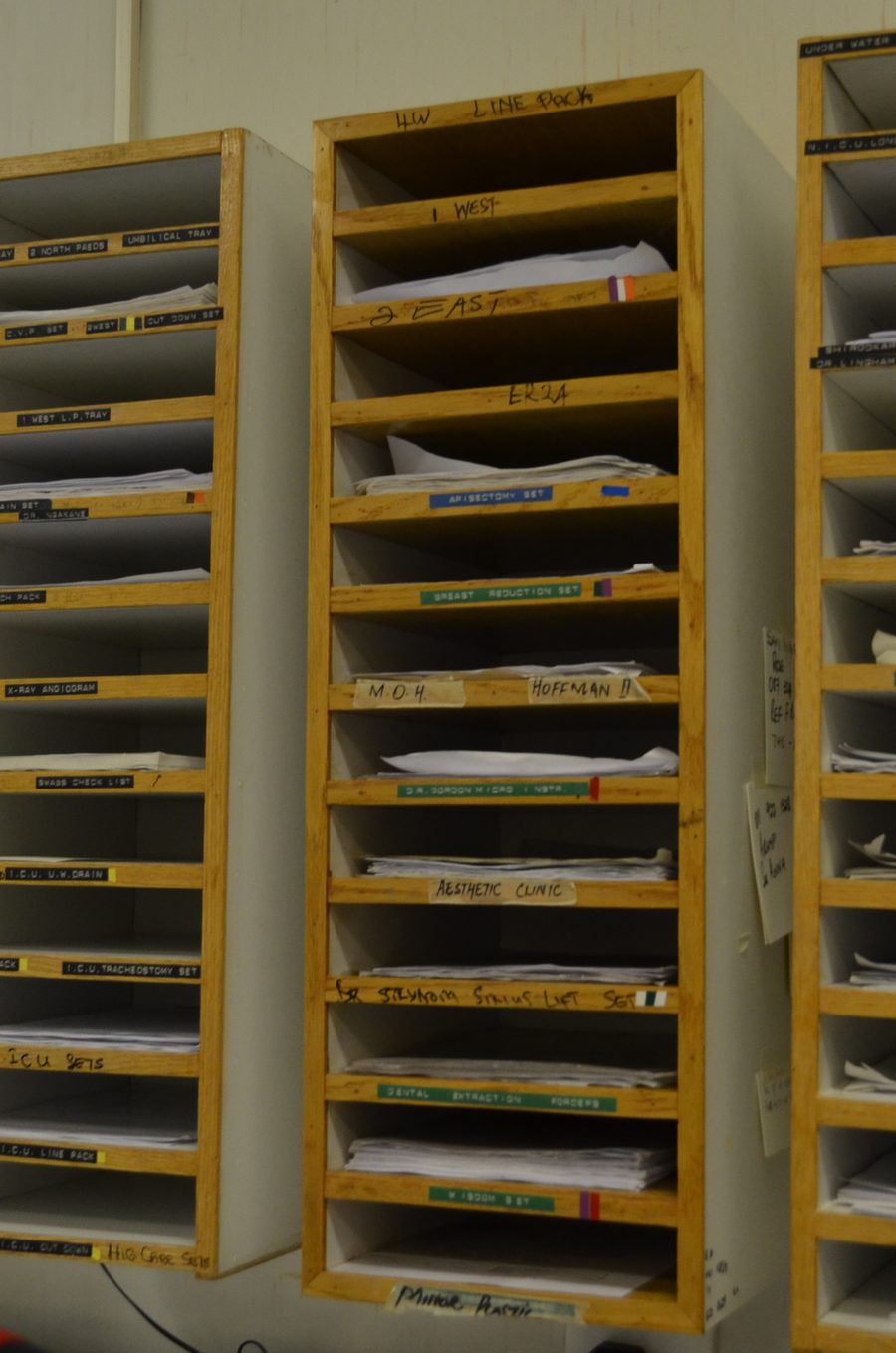 Wall-mounted wooden racks of labelled paper slots, each holding a stack of handwritten cards.