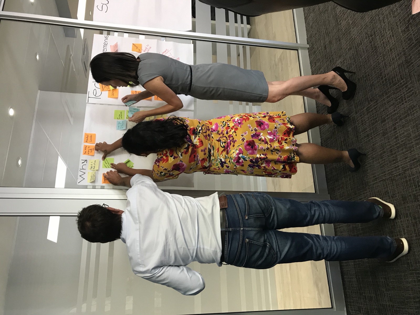 Three people building out Why and Purpose whiteboards together in a workshop room.
